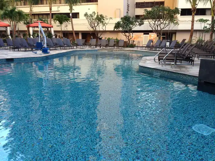 Hotel pool with refreshed blue mosaic tile and clear water ahead of the loungers