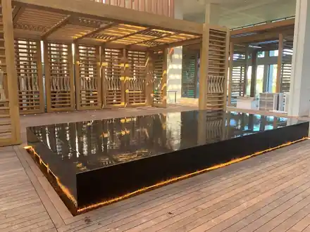 Mauna Lani raised black-tiled pool with a lit edge set into a timber deck under a slatted pavilion