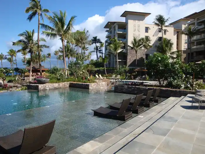 Ritz-Carlton Kapalua adult pool with in-water loungers on a stone-tiled sun shelf and lava-rock planters