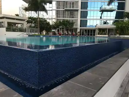 Waihonua rooftop pool with a dark-tiled spillover wall and city towers behind